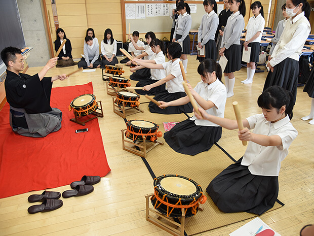 能楽の先生から太鼓の打ち方の指導を受ける生徒たち